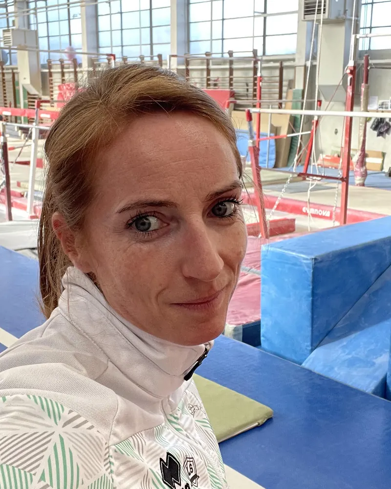 Justine Dolmaire dans un gymnase, devant les barres asymétriques